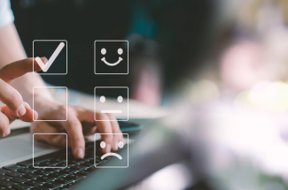 homme devant son ordinateur qui sélectionne le smiley content pour montrer sa satisfaction